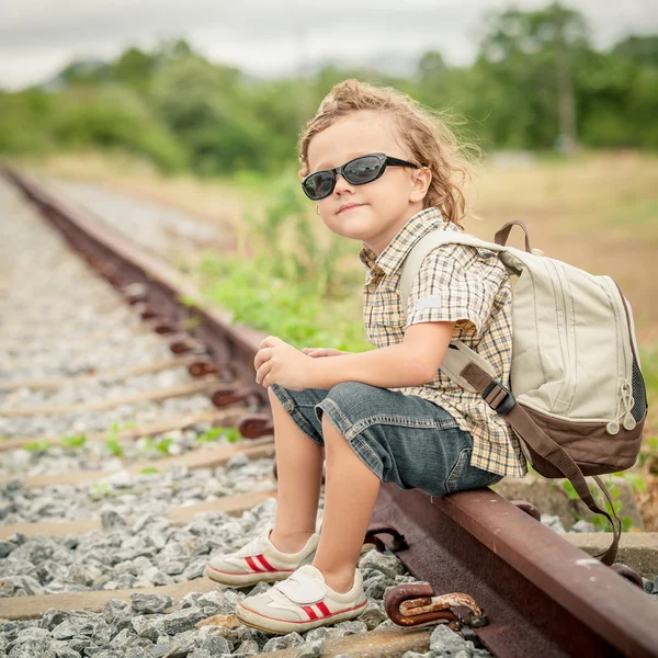 Little boy with backpack sitting on the railway — Stock Photo, Image