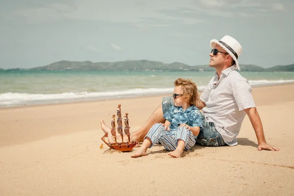 Apa és fia játszik a tengerparton nap idején. — Stock Fotó