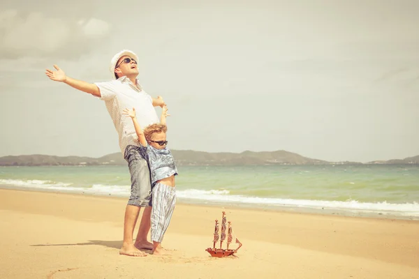 Vader en zoon spelen op het strand op het moment van de dag. — Stockfoto