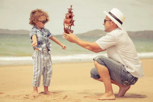 Vader en zoon spelen op het strand op het moment van de dag. — Stockfoto