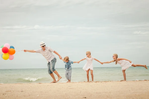 Familia feliz jugando en la playa durante el día . — Foto de Stock