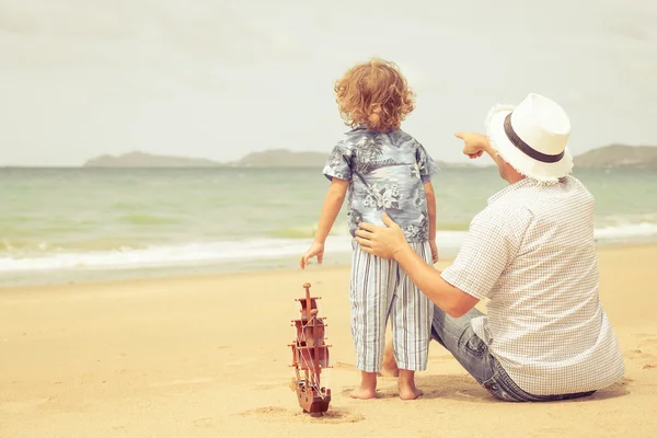 Far och son som spelar på stranden på dagarna. — Stockfoto
