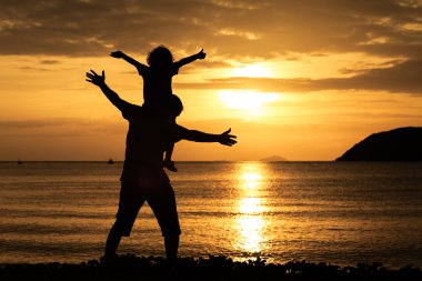 Baba ve oğul sahilde günbatımı anda oynamak.