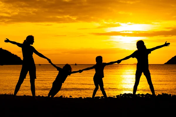 Silhouette einer glücklichen Familie, die am Strand in der Sonne spielt — Stockfoto