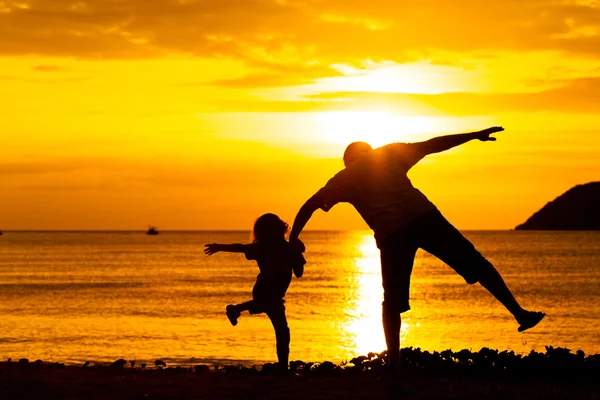 Vater und Sohn spielen am Strand bei Sonnenuntergang. — Stockfoto