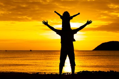 Baba ve oğul sahilde günbatımı anda oynamak.