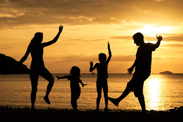 Silhueta de família feliz que joga na praia ao sol — Fotografia de Stock