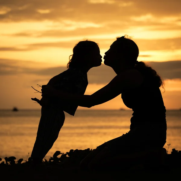 Mor och son spelar på stranden vid solnedgången tid. — Stockfoto