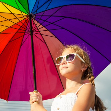 teen girl standing with umbrella on the blue sky background