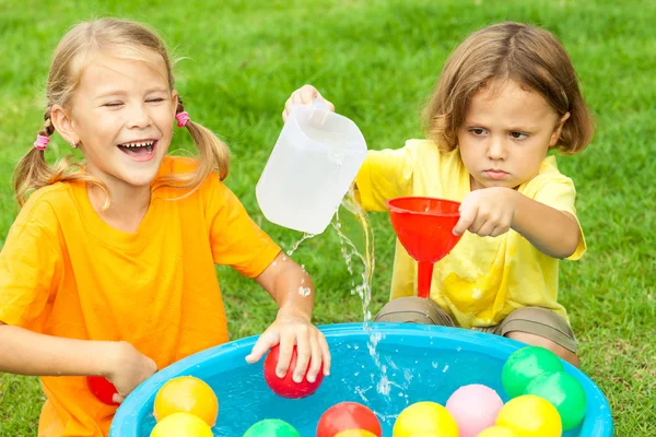 Hermano y hermana jugando con agua cerca de una casa en el día ti —  Fotos de Stock