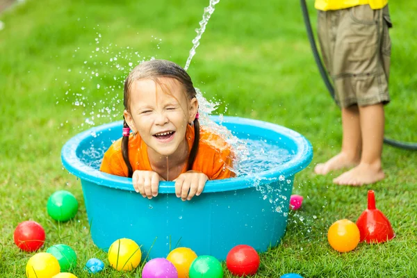 Hermano y hermana jugando con agua cerca de una casa en el día ti —  Fotos de Stock