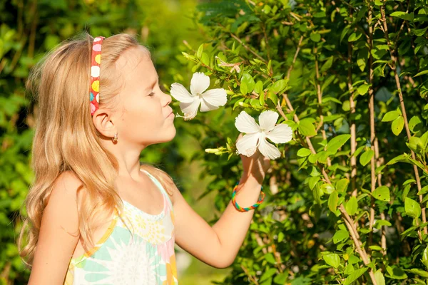 Kleines Mädchen, das Blume am Tag riecht — Stockfoto