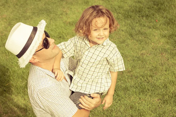 Portret een vader en zoon zittend op het gras op het moment van de dag — Stockfoto