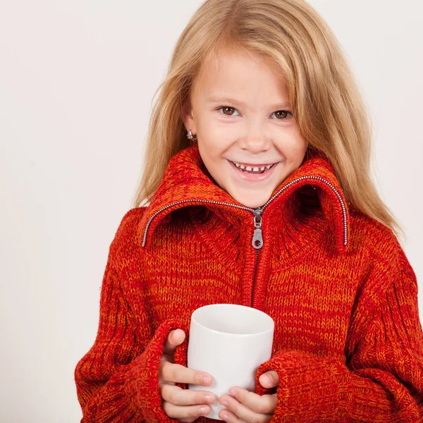 Portrait of a cute little girl in red sweater holding a mug in h — Stock Photo, Image