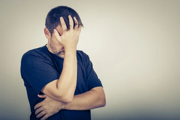 Portrait one sad man standing near a wall and covers his face — Stock Photo, Image