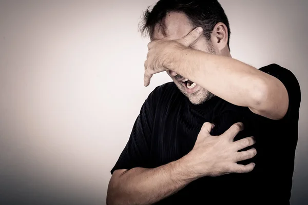 Retrato de un hombre triste de pie cerca de una pared y cubre su cara — Foto de Stock