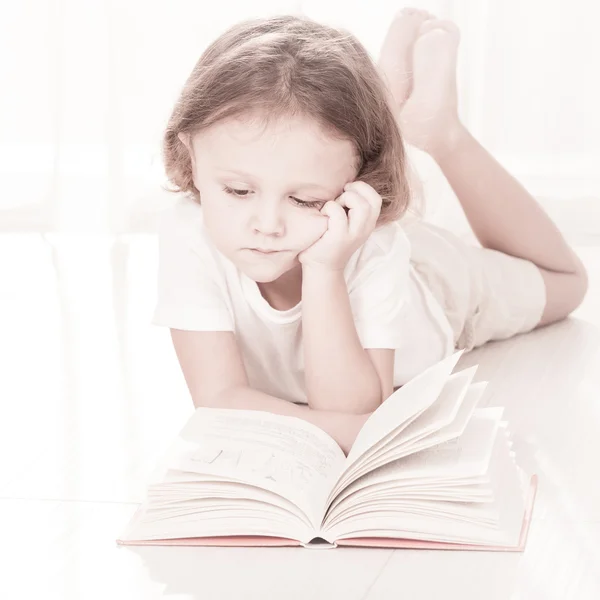 Klein kind lezen boek liggen op de vloer — Stockfoto