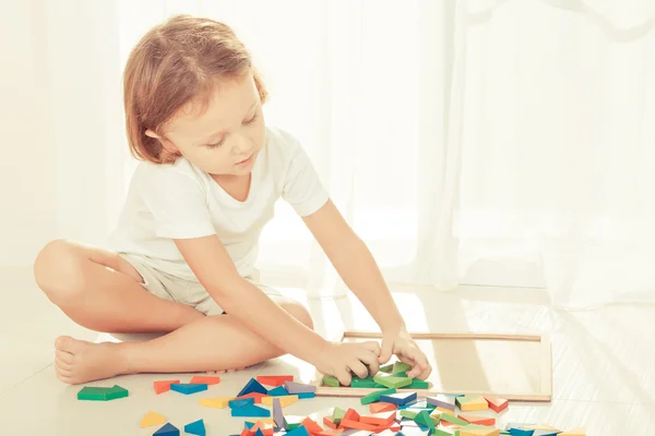 Маленький хлопчик грає з дерев'яною мозаїкою на підлозі — стокове фото