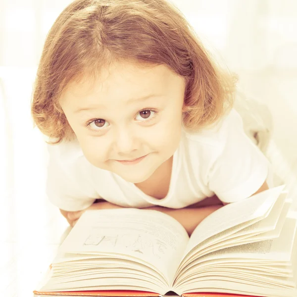 Klein kind lezen boek liggen op de vloer — Stockfoto