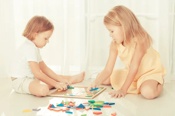 Två barn spelar med trä mosaik på rummet på golvet — Stockfoto