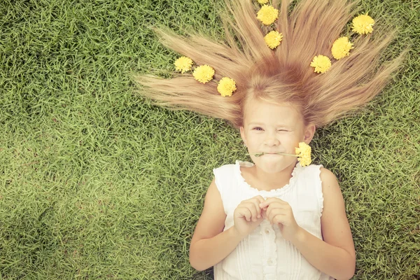 Ein glückliches kleines Mädchen auf dem Gras liegend — Stockfoto
