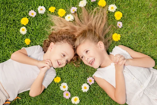 Happy little boy and girl lying on the grass — Stock Photo, Image