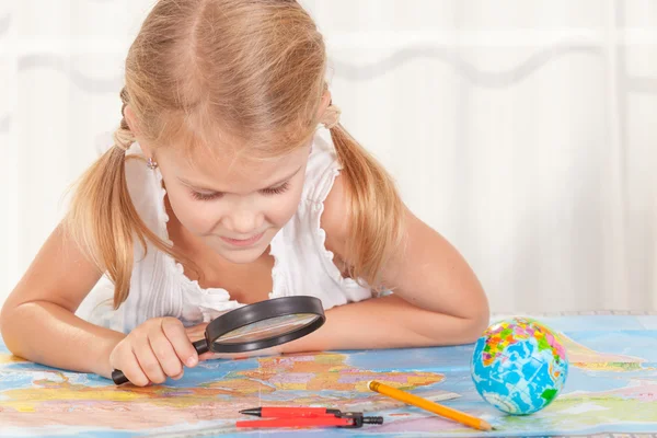 Meisje overweegt een wereldkaart met een vergrootglas — Stockfoto