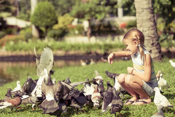 Kleines Mädchen füttert Tauben im Park — Stockfoto
