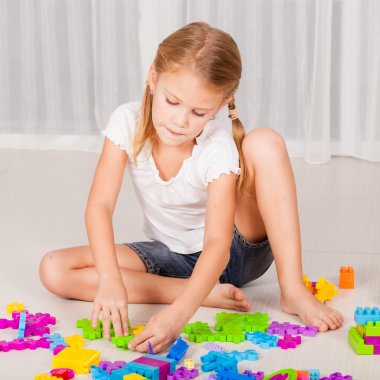 Küçük kız yere Lego oynarken