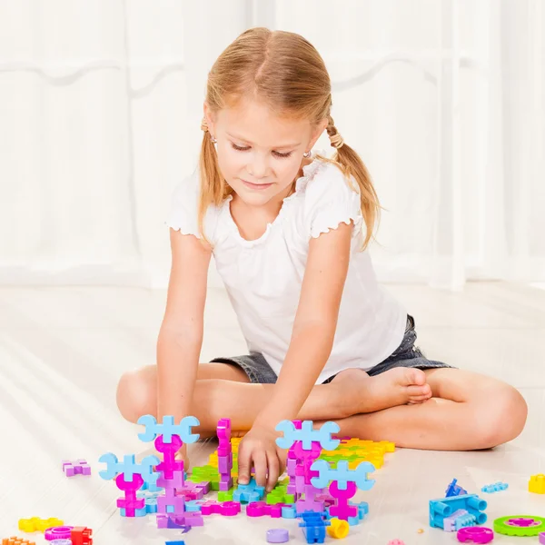 Маленькая девочка играет Лего на полу — стоковое фото