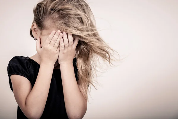 Portrait of sad blond little girl standing near wall — Stock Photo, Image