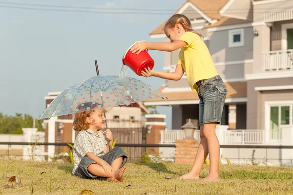 Hermano y hermana jugando con agua cerca de una casa — Foto de Stock