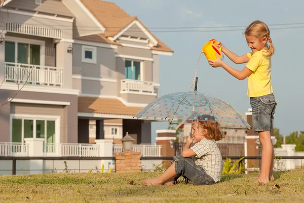 Brother and sister playing with water near a house — Stock Photo, Image