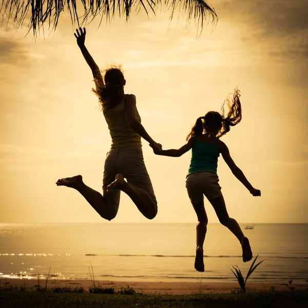 Mor och dotter hoppa på stranden — Stockfoto