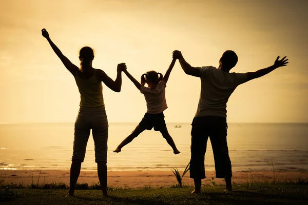 Glad familj stående på stranden vid soluppgången tiden — Stockfoto