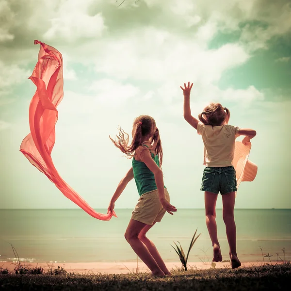 Two happy children jumping on the beach — Stock Photo, Image