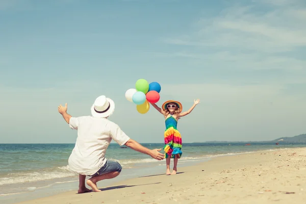 Father and daughter with balloons playing on the beach at the da — Stock Photo, Image