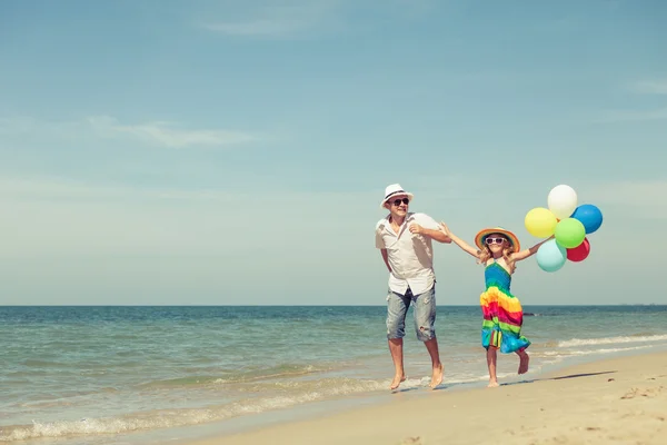 Father and daughter with balloons playing on the beach at the da — Stock Photo, Image