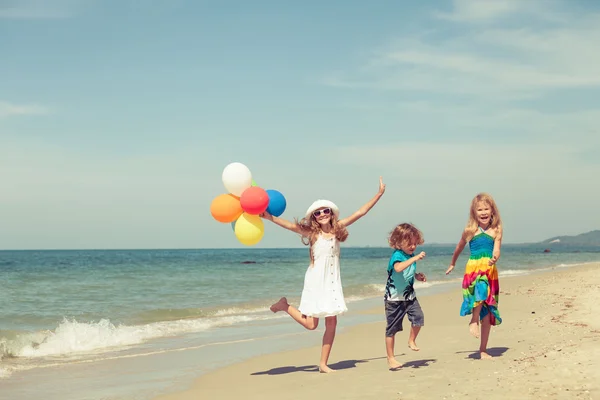 Tres niños felices bailando en la playa durante el día —  Fotos de Stock