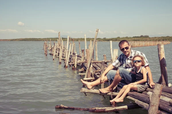 Far och son vilar på bron i havet på dagarna. — Stockfoto