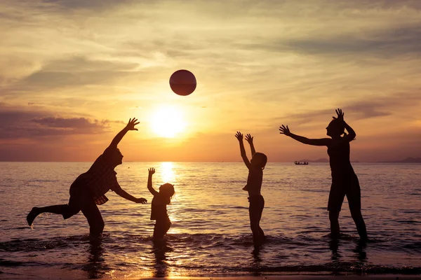 Silhouet van gelukkige familie die spelen op het strand bij de sunse — Stockfoto