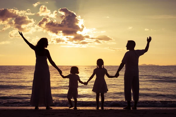 Silueta de familia feliz que juega en la playa al atardecer — Foto de Stock