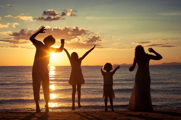 Silhueta de família feliz que joga na praia ao sol — Fotografia de Stock