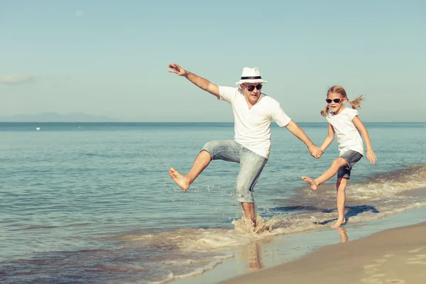 Far och dotter spelar på stranden. — Stockfoto