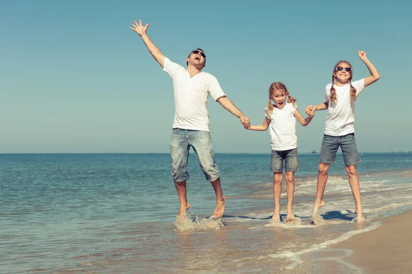 Vader en dochters spelen op het strand op het moment van de dag. — Stockfoto