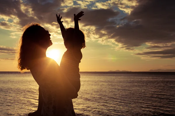 Mãe e filho brincando na praia na hora do pôr do sol . — Fotografia de Stock