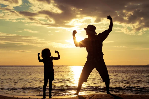 Far och son som spelar på stranden på dagarna. — Stockfoto