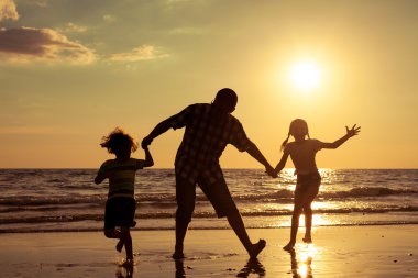 Baba ve çocuk sahilde günbatımı anda oynamak.