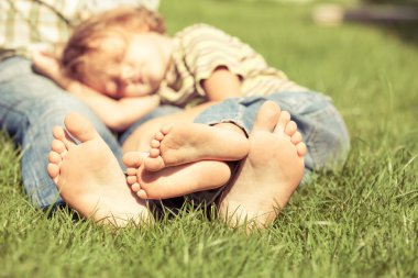 Baba ve oğul çimlere gün anda oturan.