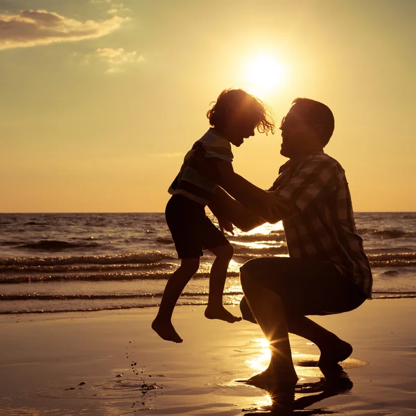 Padre e figlio che giocano sulla spiaggia all'ora del tramonto . — Foto Stock